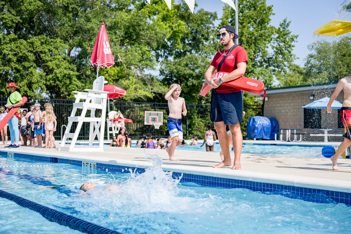 A lifeguard on duty watching swimmers at an outdoor aquatic centre.